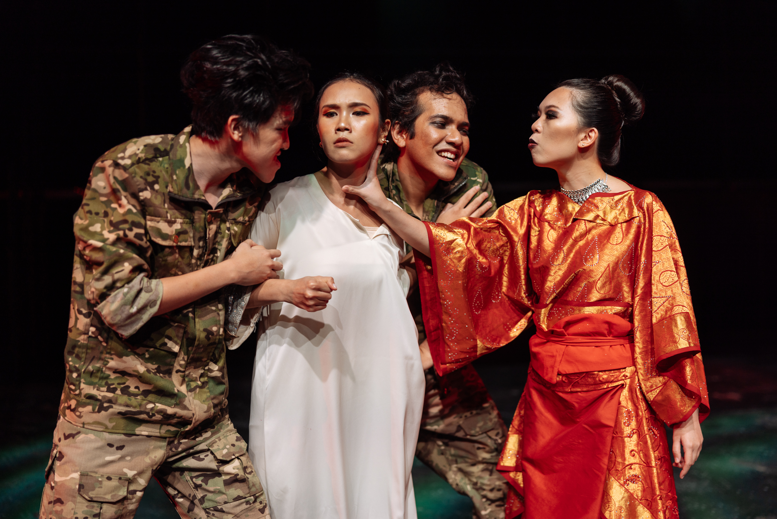 Four actors perform on stage in military, kimono and dress costumes, with one holding another’s face in a tense, dramatic moment.