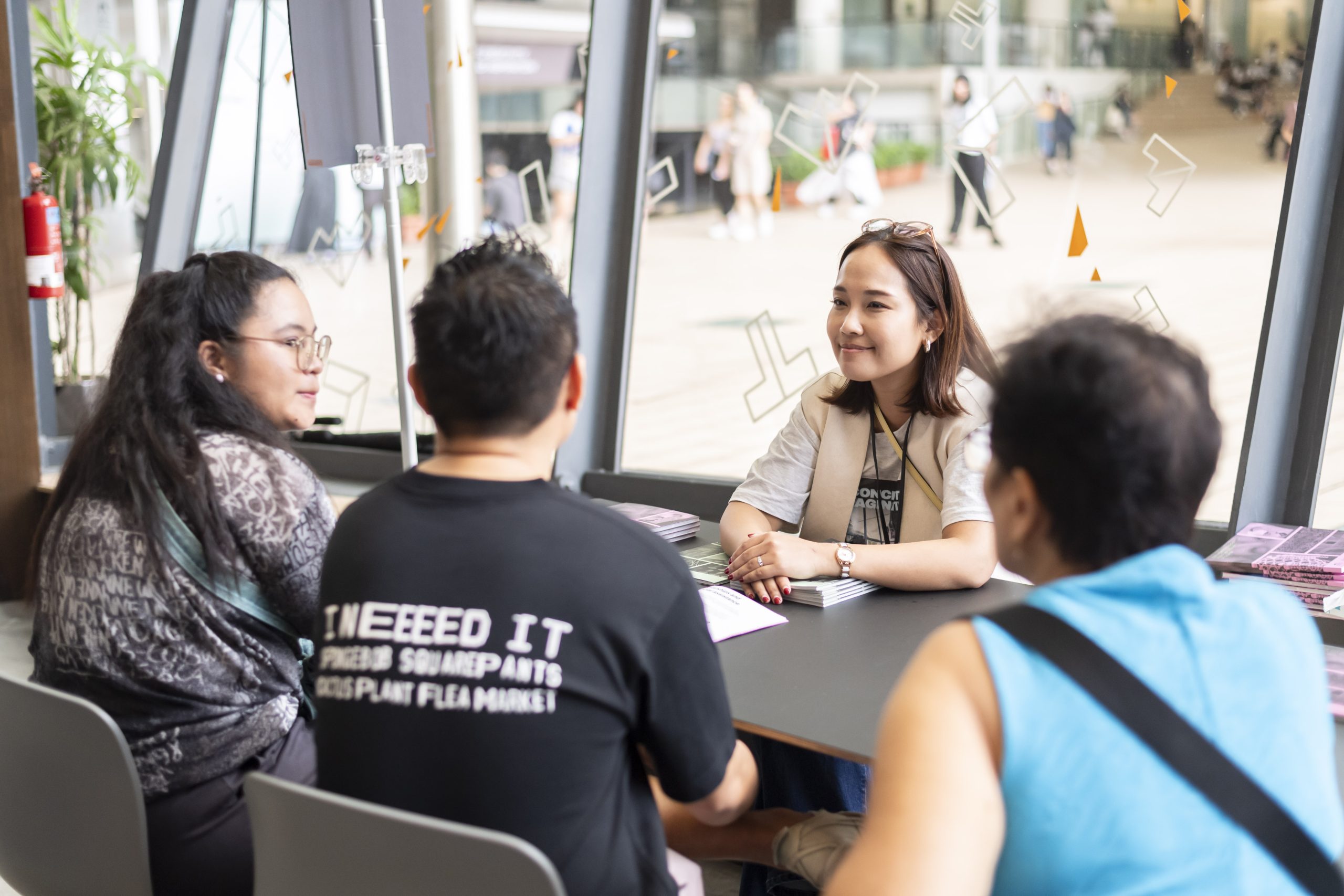 LASALLE staff member at an information booth speaking with prospective students and families during a campus event.