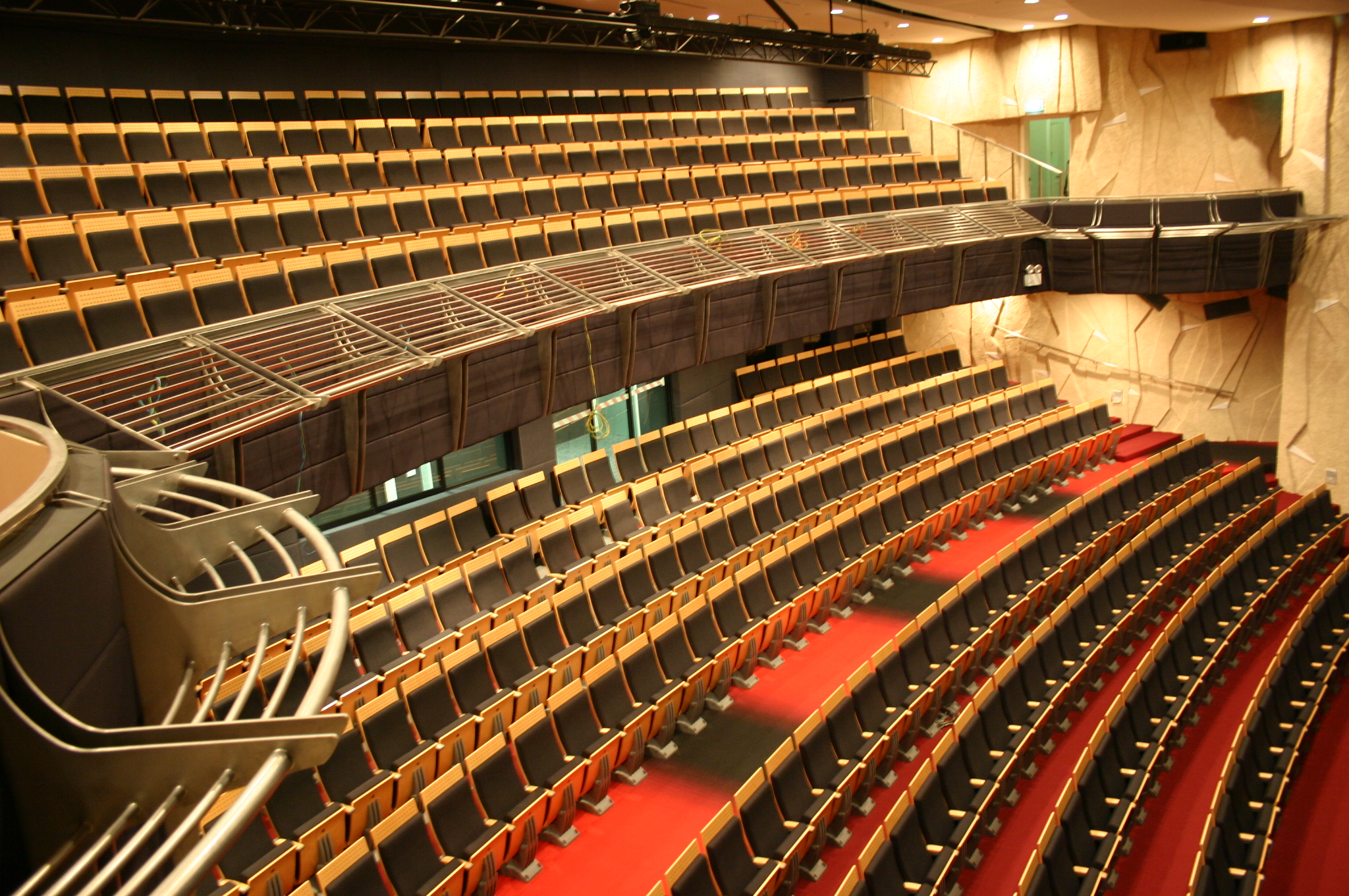 Tiered seating in the Singapore Airlines Theatre with red-carpeted aisles, curved balconies and textured walls.