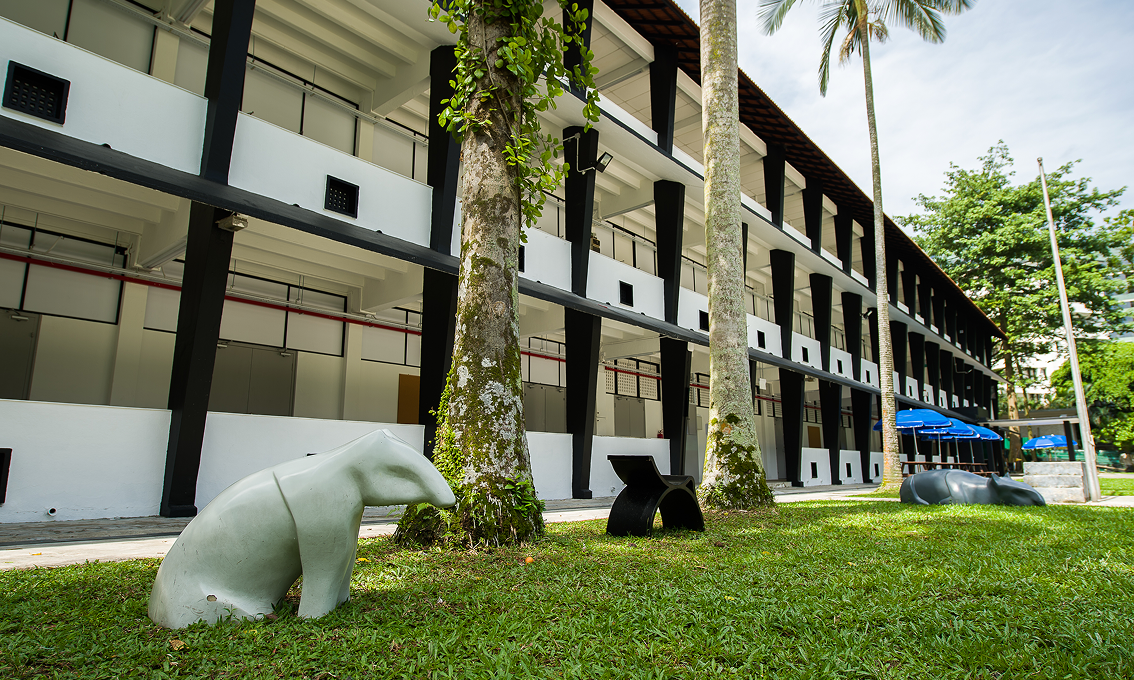 Outdoor view of LASALLE's Winstedt Campus with sculptural benches, trees and a modern black-and-white colonial-style façade.