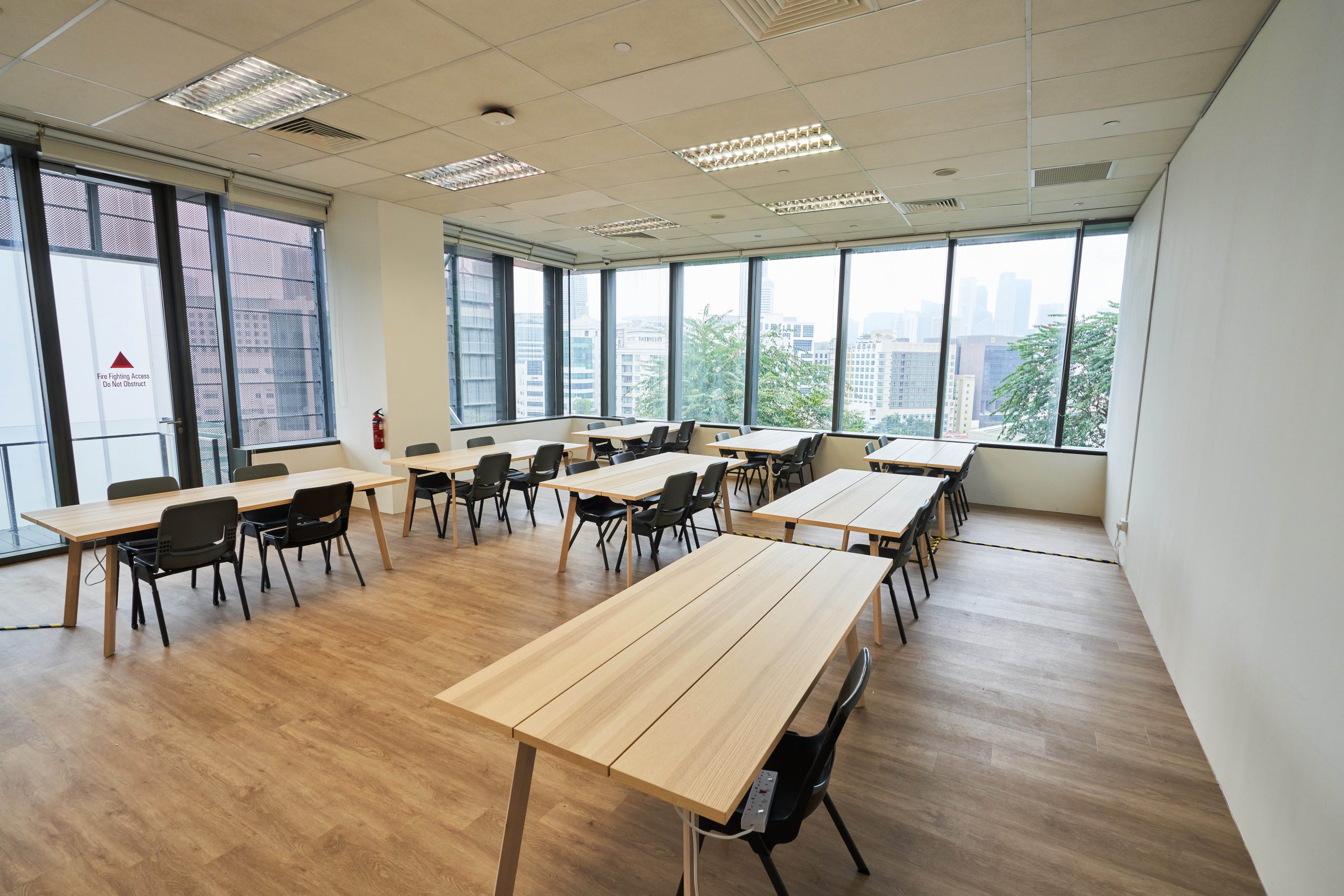 Bright classroom at Wilkie Edge with wooden floors, large windows and modular tables arranged in clusters.