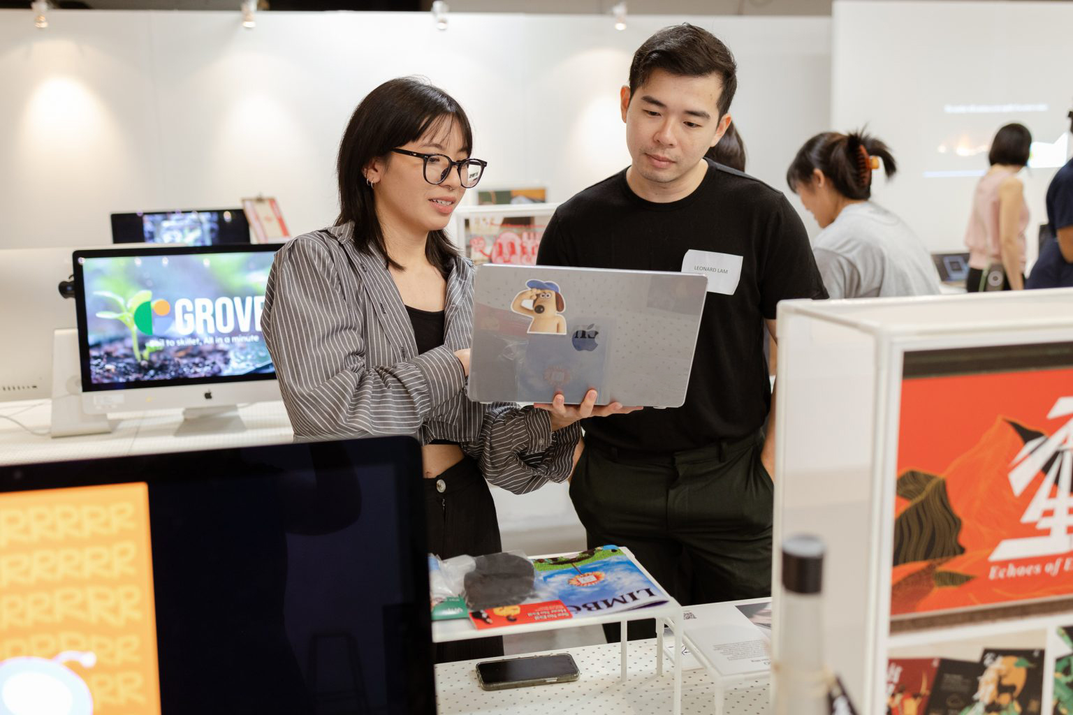 A LASALLE career services team member shares on a laptop to a student, surrounded by screens and creative projects.